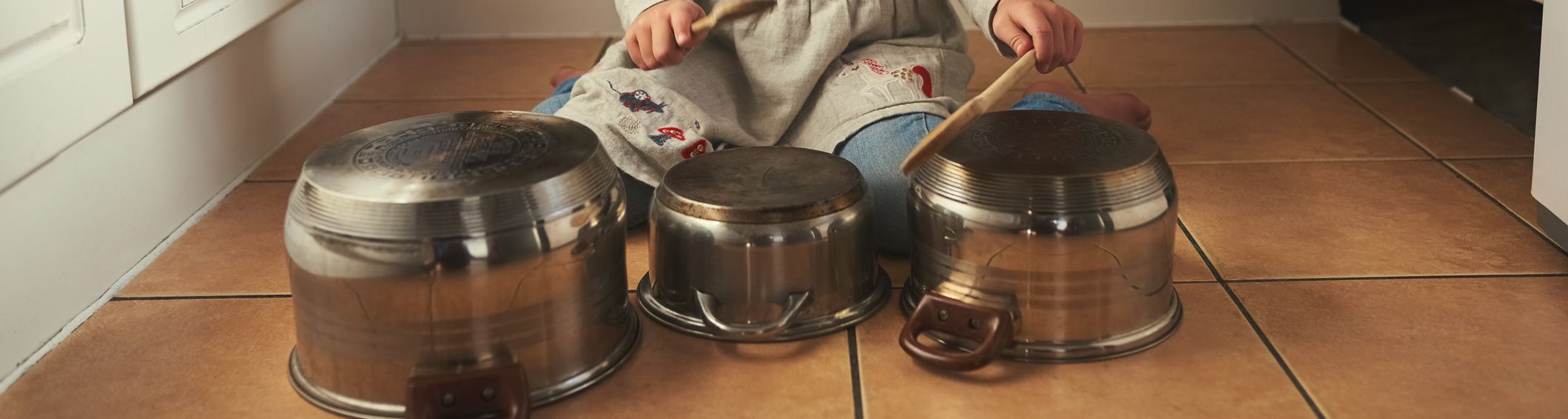 Shot of a little girl playing drums on a set of pots in the kitchen